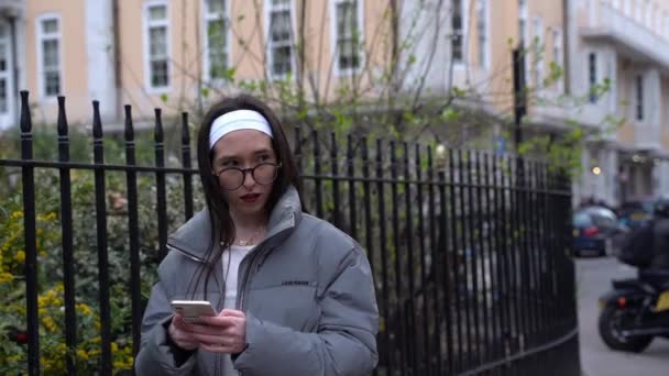 女孩走在街上 看着智能手机 看起来很害怕 看着周围的环境 慢动作中弹 — 图库视频影像