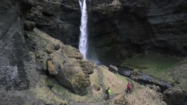 在冰岛 有两个人爬上覆盖在峡谷上的绿色苔藓 到达海燕瀑布 — 图库视频影像