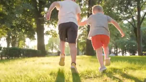 公園で走っている2人の少年と地面でつまずく1人の少年 ジンバルはカメラから逃げる撮影に従います — ストック動画