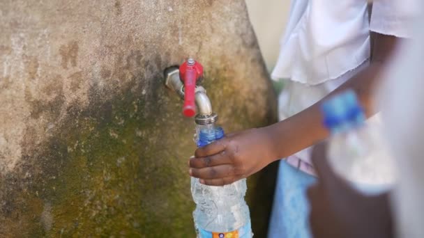 噴水で水のペットボトルを満たすアフリカの黒い子供たちの映画的なショットを閉じます アフリカの水と資源不足 — ストック動画