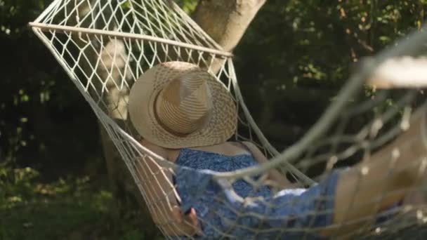 Woman Face Covered Straw Hat Rests Peacefully While Swinging Hammock — Αρχείο Βίντεο