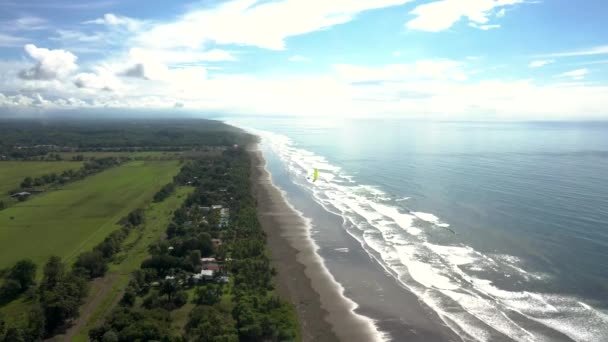 コスタリカの海岸のビーチを飛んでパラグライダーの空中ビュー — ストック動画