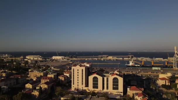 貨物クレーンと船で港への建物の複合体上の無人機飛行日没と海 ハイファ イスラエルと水平線 — ストック動画