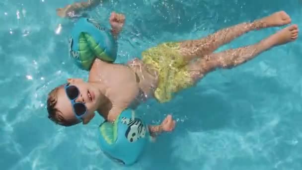Relajado Niño Pequeño Con Gafas Sol Flotando Piscina Con Flotadores — Vídeos de Stock