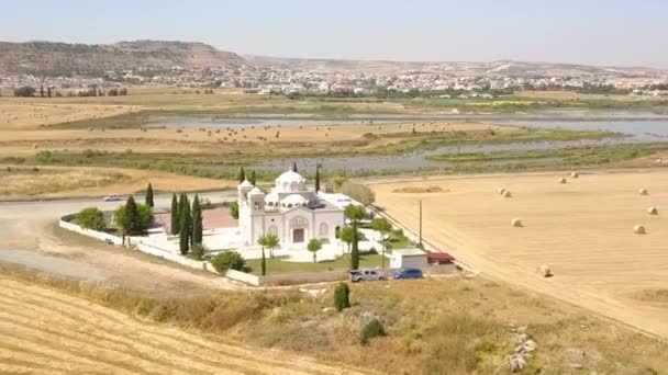 見事な湖の背景を持つ美しい白い教会に向かってドローン飛行 ラルナカ市 キプロス — ストック動画