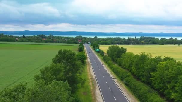 Samochód Pochodzi Jeziora Autostradzie Pięknym Tle Deszczowym Drone Materiał — Wideo stockowe