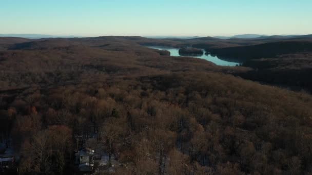 회전하면서 겨울철해 숲으로 뒤덮인 과산의 호수와 시골에 집들의 경치가 드러납니다 — 비디오