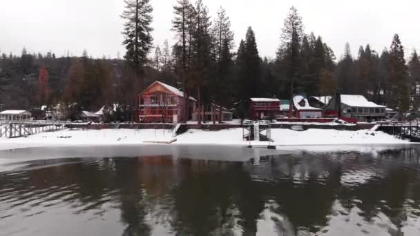 Pan Right Shining Lake Winter Houses Docks Snowy Shore — Stockvideo