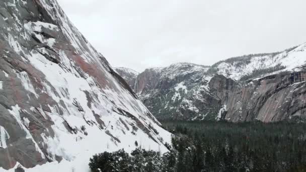 飞越约塞米蒂山谷上空的无人驾驶飞机镜头 冬季被白雪覆盖的花岗岩悬崖峭壁所覆盖 — 图库视频影像