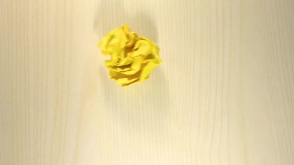 黄色い紙の玉が捨てられ軽い木の背景に着陸しアニメ化された線がそこから光線で電球を作り出し — ストック動画