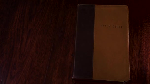 从上往下拍摄一本皮制装订的圣经 在一张木制桌子上被打开 翻到约翰的第一本书上 — 图库视频影像