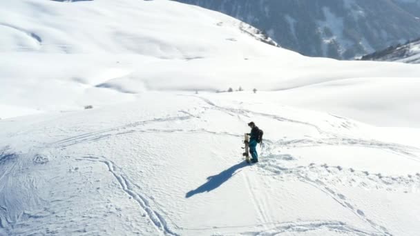 空中の景色 雪に覆われた山の上に立つスノーボーダーの周りに喘ぐ — ストック動画