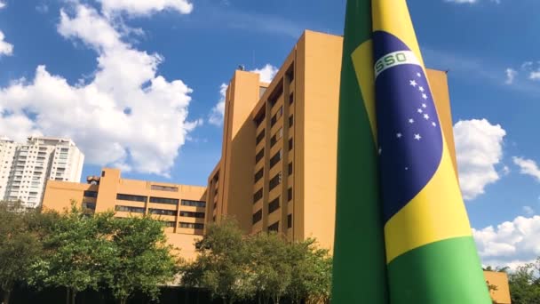 Brasilianische Flagge Weht Zeitlupentempo Park Mit Gebäuden Und Blauem Himmel — Stockvideo