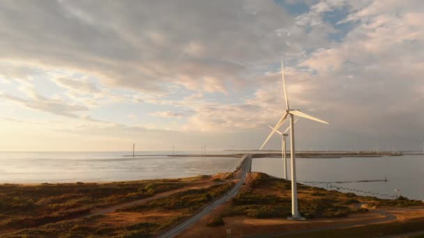 荷兰西南部日落期间的风力涡轮机 有太阳光的动态航拍 从右到左 高于地面 — 图库视频影像