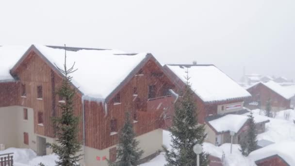 スキー場の家に吹雪が吹いて視界が悪くなり 雪の結晶がたくさんあります — ストック動画