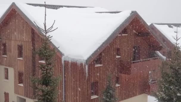 雪とつららに覆われた背の高いシャレーでスキー場に吹く強い雪嵐 — ストック動画