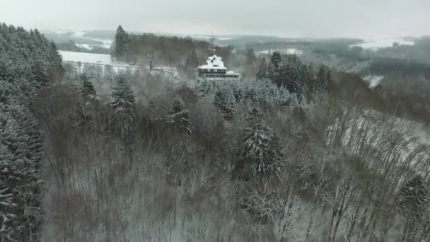 冬天来到了一座被雪覆盖的山顶上的一座废弃旅馆 空中的景色掠过美丽的积雪覆盖的树木 — 图库视频影像