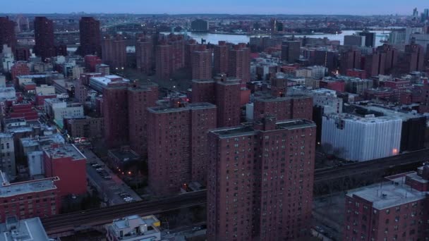 庄严的无人驾驶飞机横穿纽约市哈莱姆社区 俯瞰许多天台 高架列车转向市中心的天际线 日落的时候是蓝色的In — 图库视频影像