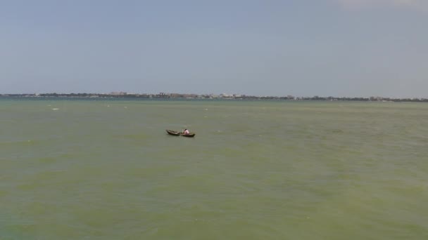 タンザニアのダルエスサラーム市の海岸近くの晴れた日の波に木製の漁船を漕ぐ男 — ストック動画