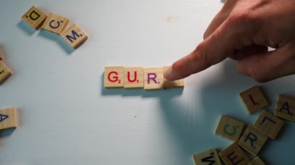 Een Tafel Met Verspreide Houten Letters Een Persoon Die Goeroe — Stockvideo