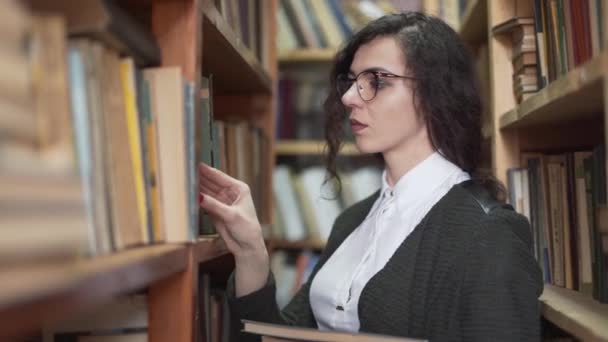 Trött Allvarlig Vacker Lärare Plocka Böcker Från Hylla Ett Bibliotek — Stockvideo