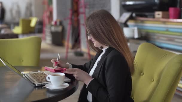 Biznes Kobieta Sącząc Kawę Podczas Robienia Notatek Przed Laptopem Kawiarni — Wideo stockowe