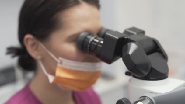Dentista Feminina Com Máscara Boca Olhando Trough Dental Microscope Binóculos — Vídeo de Stock