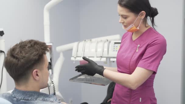 Dentista Femenina Uniforme Púrpura Guantes Negros Explica Fisiognomía Los Dientes — Vídeos de Stock