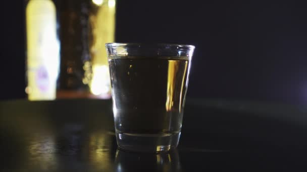Arka Planda Bir Şişe Viskiyle Bir Shot Bardağının Dönen Silueti — Stok video
