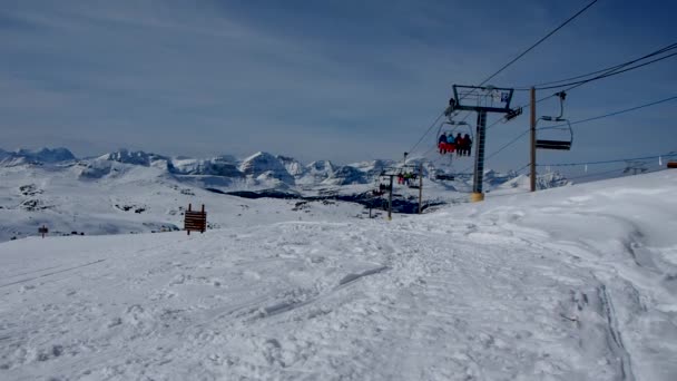 在雪山上的滑雪胜地坐着轮椅 滑雪者走过 — 图库视频影像
