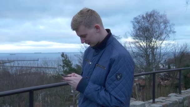 Paning Shot Młody Blondynka Mężczyzna Pisanie Sms Jego Smartfon Koncentracją — Wideo stockowe