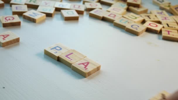 Table Scattered Wooden Letters Person Spelling Play White Background Dramatic — Αρχείο Βίντεο