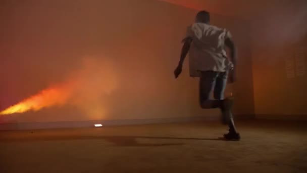 一个穿着便帽的非洲年轻人跳着舞步跳着风车 在五彩缤纷的迪斯科灯光和烟雾中跳着双手的慢镜头 — 图库视频影像