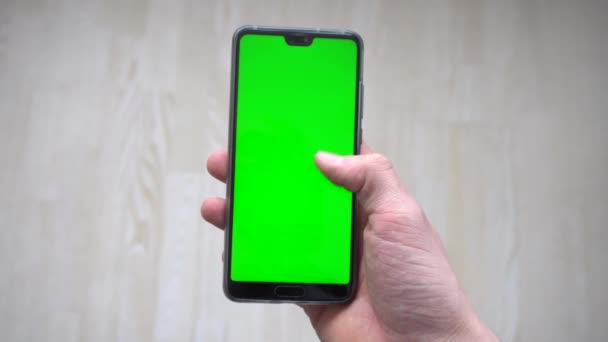 緑色のスクリーンを持った電話を持っていて指先でスクロールしている人 — ストック動画