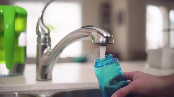 台所の蛇口から水のボトルを満たす手 — ストック動画