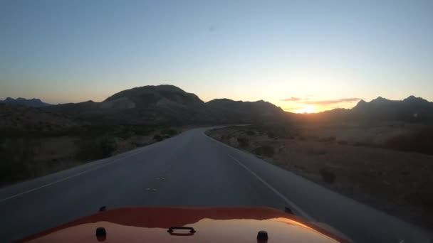 Jadąc Kierunku Wschodu Słońca Czerwonym Pojazdem Pustyni Widocznymi Górami Sylwetce — Wideo stockowe