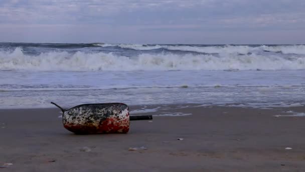 在外滩冲到岸上的一只商业螃蟹罐子里的浮标标记 海滩上的垃圾 背景是夕阳西下波涛汹涌 低角度 靠近点 — 图库视频影像