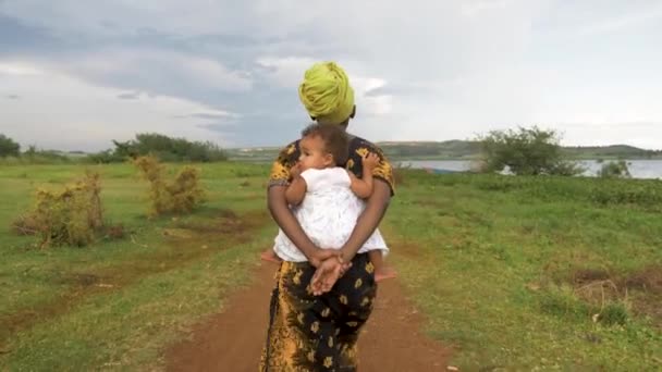 Sledovací Záběr Zezadu Africké Matky Kráčející Prašné Stezce Svým Dítětem — Stock video