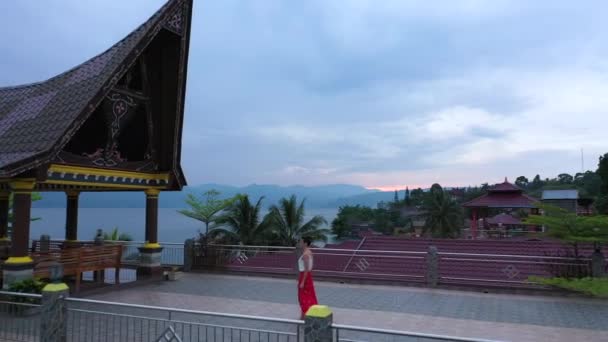 印度尼西亚苏门答腊岛北部托巴湖畔的一处海滨度假胜地 一名妇女在日出时分穿过砖瓦屋顶的镜头 系列2 — 图库视频影像