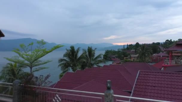 印度尼西亚苏门答腊岛北部托巴湖畔的一处海滨度假胜地 一名妇女在日出时分穿过砖瓦屋顶的镜头 系列1 — 图库视频影像