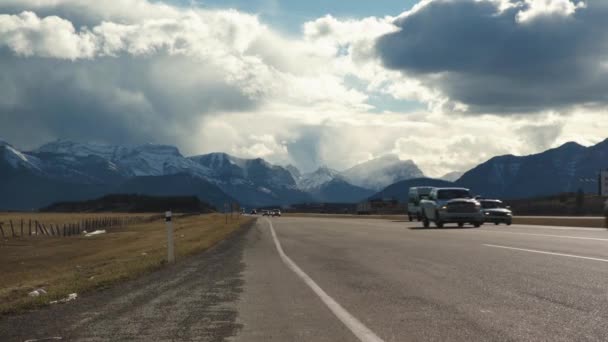 いくつかの車は道路の側面に美しい山々といくつかのゴミと高速道路で過去のカメラを駆動します — ストック動画