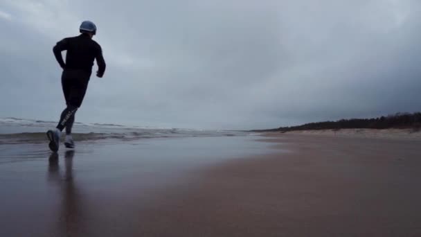 Νεαρός Τρέχει Στην Παραλία Και Πατάει Στο Νερό Μετά Από — Αρχείο Βίντεο