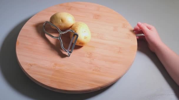 Hände Eines Kleinen Mädchens Beim Kartoffelschälen Mit Schäler Auf Holztisch — Stockvideo