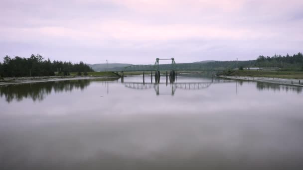 ドローンは非常に低く飛行し オレゴン州の近くのバンドンのコキル川を渡ってブラルズ橋へとゆっくりと進みます 光は日の出から紫色です 雲は水に反射する — ストック動画