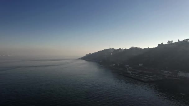 海のそばの山 リスボン川の対岸にあるアルマダ市 霧の朝にドローンが撃たれた パノラマエレベーターの近くの山の頂上を通る光線 — ストック動画