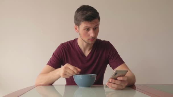 Man Reagerar Innehåll Mobiltelefon Medan Man Äter Spannmål Sittande Vid — Stockvideo