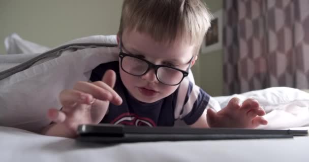 Шестилетний Мальчик Читающий Планшет Лежа Постели — стоковое видео