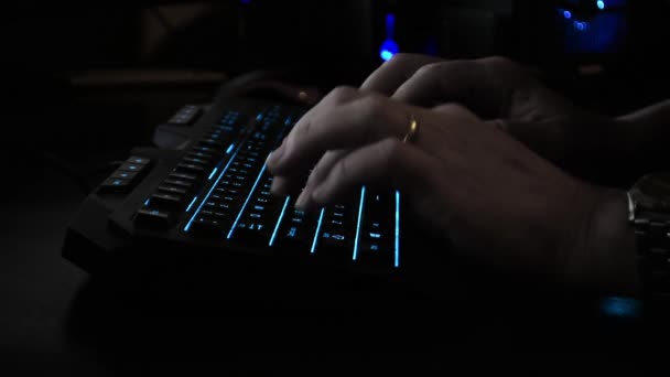一个网络罪犯的手在背光键盘上打字的侧视图 黑暗的办公室 — 图库视频影像