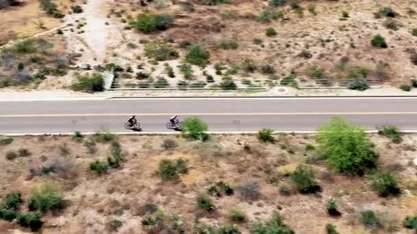 Aerial Dwóch Rowerzystów Jadących Wzdłuż Drogi Wzdłuż Otwartej Pustyni Sonoran — Wideo stockowe