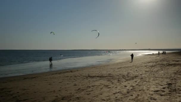 Twee Kitesurfers Enkele Mensen Bij Zonsondergang Het Strand — Stockvideo